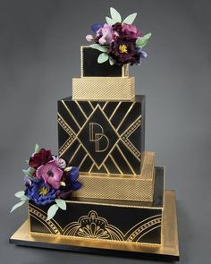 a three tiered black and gold wedding cake with purple flowers on the top layer