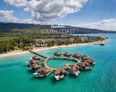 an aerial view of the beach and water with huts on it, surrounded by palm trees