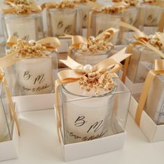 many small white boxes with brown bows and labels on them are sitting on a table