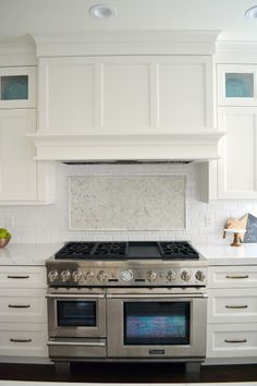 a stove top oven sitting inside of a kitchen next to white cabinets and counter tops