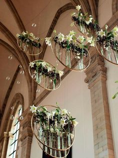 several hanging vases filled with flowers and greenery