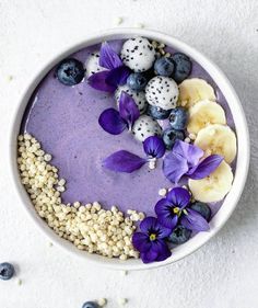 a bowl filled with blueberries, bananas and other foods on top of a white surface