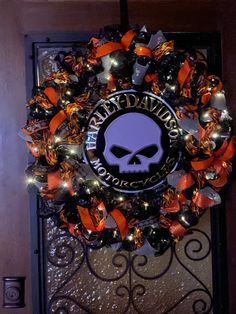 a halloween wreath with an image of a skull and orange ribbon on the front door