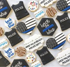 decorated police cookies are displayed on a white tablecloth with the words police written in black, blue and white