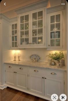 an image of a kitchen setting with white cabinets and marble counter tops, along with wood flooring