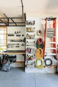 the garage is filled with various tools and equipment, including hoses hanging on the wall