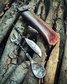 a knife and two spoons sitting on top of a tree trunk