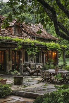 an outdoor patio with tables, chairs and potted plants in front of a house