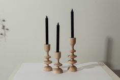 three wooden candlesticks sitting on top of a white table