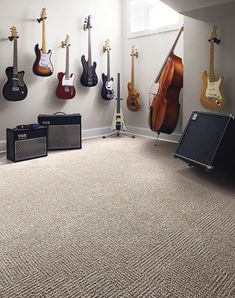 guitars and amps are lined up against the wall in this music studio with carpeted flooring