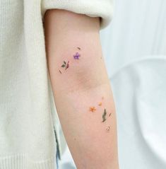 a woman's arm with small flowers on the left side of her arm,