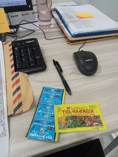 a desk with a keyboard, mouse and other items on top of it next to an open book