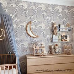 a baby's room with a crib, dresser and wallpaper