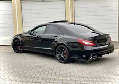 a black mercedes cls parked in front of two garage doors