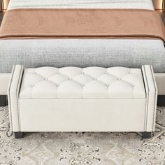 a white bench sitting on top of a carpeted floor next to a large bed