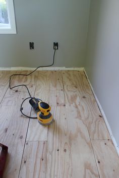 a corded sander is on the floor in an empty room with no walls