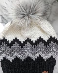 a black and white hat with a grey pom - pom on the top