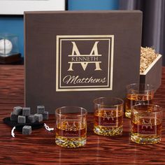 four whiskey glasses sitting on a table next to a box with the name marthennes