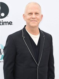 a bald man in a black suit and white t - shirt