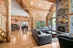 a living room filled with furniture and a fire place in the middle of a wooden floor