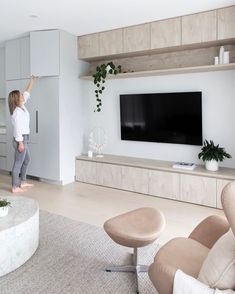 a woman standing in front of a flat screen tv next to a living room filled with furniture