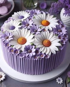 a cake with purple icing and white flowers on the top is sitting on a plate