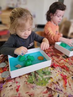 two young children playing with toys on a table