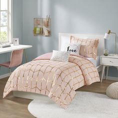 a bed with pink comforter and pillows on top of it in a room next to a window