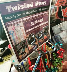 a person holding up a bunch of toys in front of a sign that says twisted pens made by navrie high school esl students