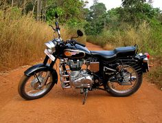 a motorcycle parked on the side of a dirt road