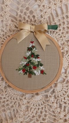 an embroidered christmas tree on a piece of fabric with a bow hanging from it's side