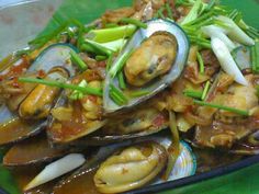 a green plate topped with clams covered in sauce