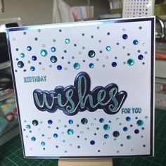 a handmade birthday card with the word wishes in blue and green glitters on it