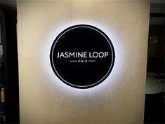 a sign that says jasmine loop hair on the side of a wall