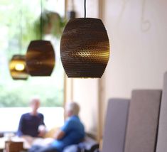 two people sitting at a table in a room with lights hanging from it's ceiling