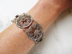 "This is a lovely vintage filigree bracelet. Made of sterling silver, the circle links all have a center raised flower inside a sunburst/snowflake design. The links are 1\" in diameter. The length of the bracelet is 8 1/4\" long. The large spring ring clasp is secure. Total weight of the bracelet is 16.2dwt/25.1grams. This is a vintage, previously owned bracelet. Therefore, light wear can be expected. There is no visible damage." Round Solitaire Diamond Necklace, Filigree Bracelet, Vintage Sterling Silver Charms, Carved Heart, Sterling Silver Charm Bracelet, Snowflake Design, Sterling Silver Filigree, Silver Charm Bracelet, Bracelet Vintage