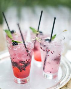 three glasses filled with drinks sitting on top of a white plate