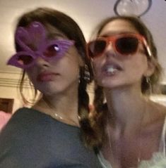 two women wearing sunglasses and one has a flower in her eye