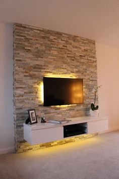 a living room with a television mounted on the wall and some lights in front of it