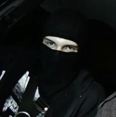 a woman wearing a black veil and head covering in the back seat of a car