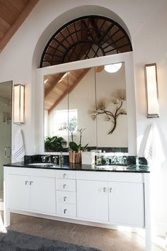 a bathroom with double sinks and large mirror above it's countertop, along with an arched doorway leading to another room