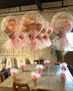 pink and gold balloons with name on them sitting on a table in front of a brick wall