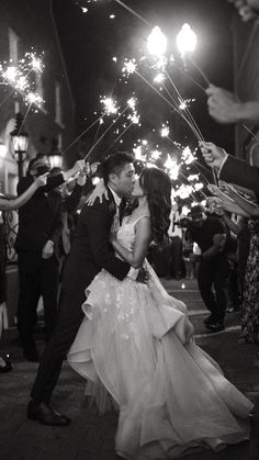 a bride and groom kissing while holding sparklers