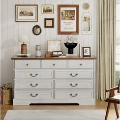 a white dresser with many pictures on the wall