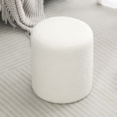 a white stool sitting on top of a carpeted floor next to a rug covered in tassels