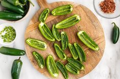 green peppers are on a wooden cutting board next to other vegetables and seasoning supplies