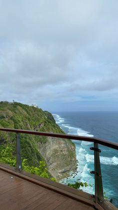 a woman standing on top of a wooden deck next to the ocean