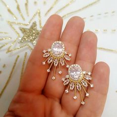 a person holding two pairs of earrings in their hand