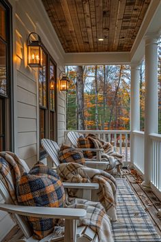 the front porch is lined with chairs and blankets on it, along with fall foliage