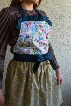 "An adorable handmade apron with Texan pride! The bodice features pleats - to give this apron some personality! When you wear this apron - you feel like you can cook, bake, or craft anything - while also feeling cute! The bodice is lined, no raw edges of fabric are exposed - made well and made to last.  The skirt is gathered.  The waistband ties can be used to create a bow tie in either the front or back of apron.  100% Cotton. Machine washable. I recommend to hang to dry, but can be placed in d Cooking Aprons, Handmade Aprons, Pleated Bodice, Cooking Apron, Blue Bonnets, Bright Designs, Gathered Skirt, Linen Apron, Neck Strap